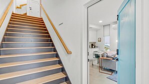 A modern staircase with wooden steps and a handrail, leading to a room with a desk, chair, and a view of the outside. - Mini Metro - Downtown Rooftop with Skyline View! (Raleigh)