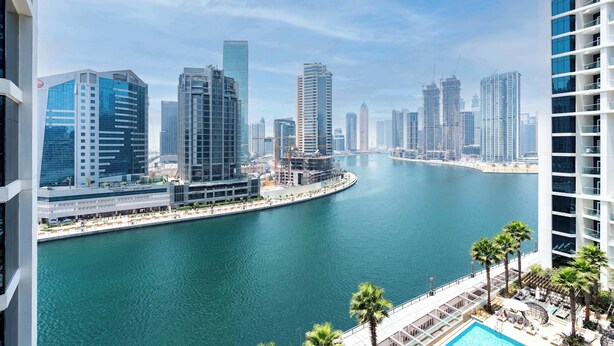 A high-rise hotel overlooking a marina with modern buildings and a clear sky. - Luxury Canal-View Studio (Business Bay)