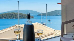 A balcony with a view of the sea, two glasses of wine, and a wine bottle. - MANDRAGORAS ECO FRIENDLY (Perigiali)