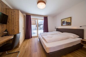 A hotel room with a wooden desk, a bed, a TV, and a window with curtains. - Chalet in Neukirchen Near Ski Arena Wildkogel (Neukirchen am Grossvenediger)
