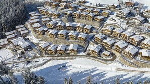 Ein schneebedecktes Resort mit mehreren Chalets, die kreisförmig um einen zentralen Innenhof angeordnet sind.