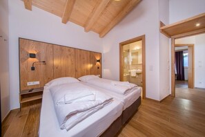 A bedroom with two beds, wooden headboard, and a mirror. - Chalet in Neukirchen Near Ski Arena Wildkogel (Neukirchen am Grossvenediger)