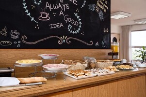 Un bufé de desayuno con diversas opciones de comida y una pizarra con mensajes inspiradores.