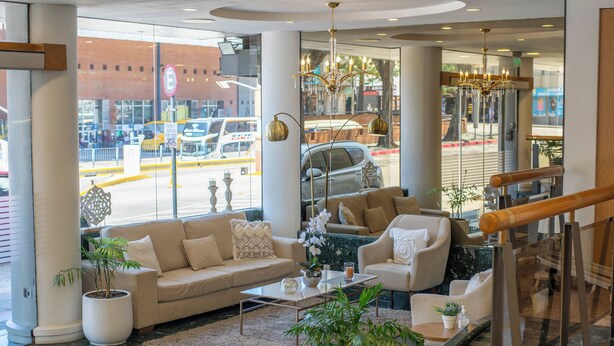 Un moderno vestíbulo de hotel con un sofá, sillones, una mesa de centro y plantas en macetas.