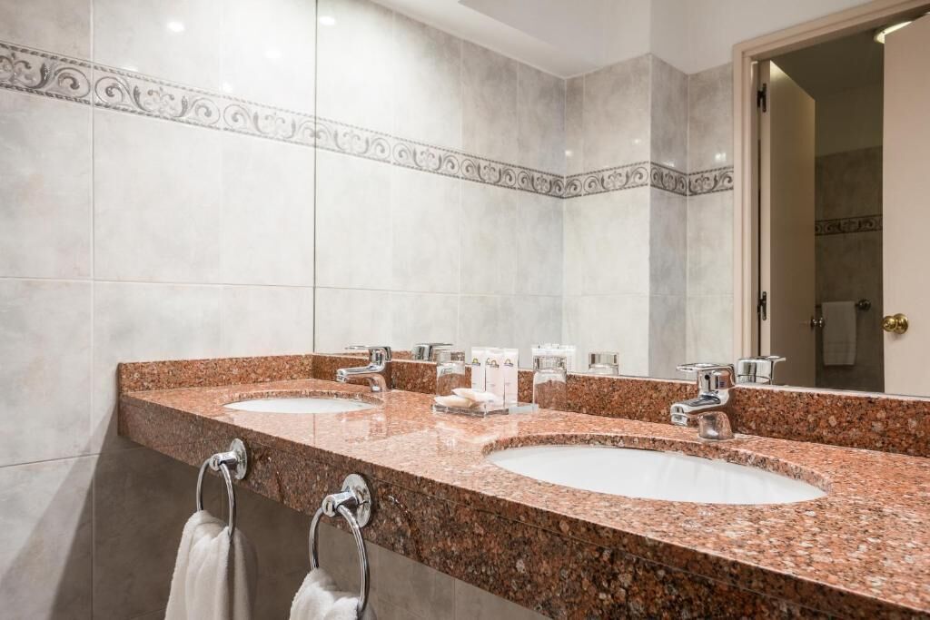 Un baño con dos lavamanos, un espejo y un perchero para toallas.