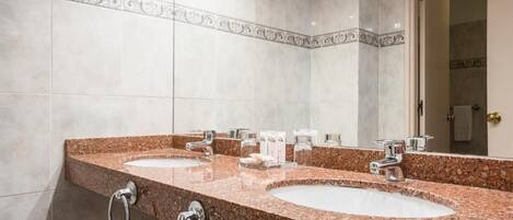 Un baño con dos lavamanos, un espejo y un perchero para toallas.
