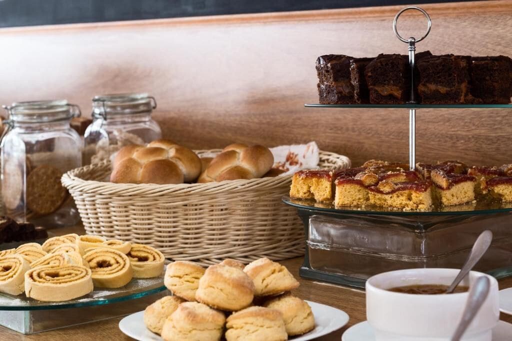 A buffet with various baked goods including pastries, bread rolls, and desserts.