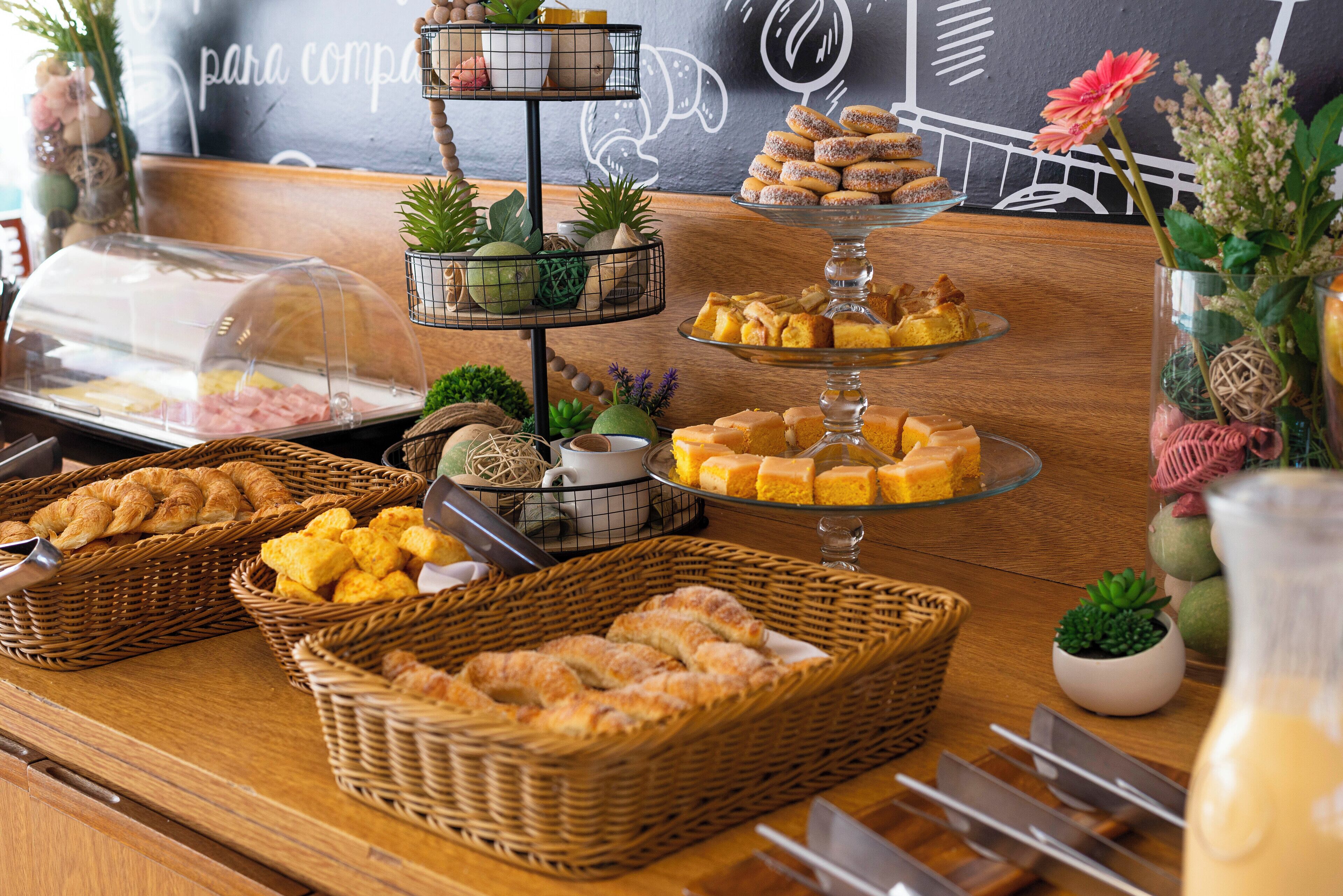 Una mesa de buffet con diversas opciones de comida, incluyendo pasteles y postres, dispuesta sobre una barra de madera.