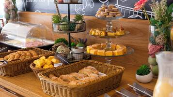 Una mesa de buffet con diversas opciones de comida, incluyendo pasteles y postres, dispuesta sobre una barra de madera.