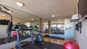 Un gimnasio con cintas de correr, pelotas de ejercicio y un espejo grande.
