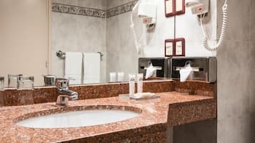 Un baño con lavamanos de granito, un espejo, un perchero y un secador de pelo.