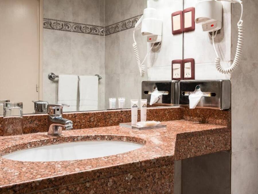 Un baño con lavamanos de granito, un espejo, un perchero y un secador de pelo.