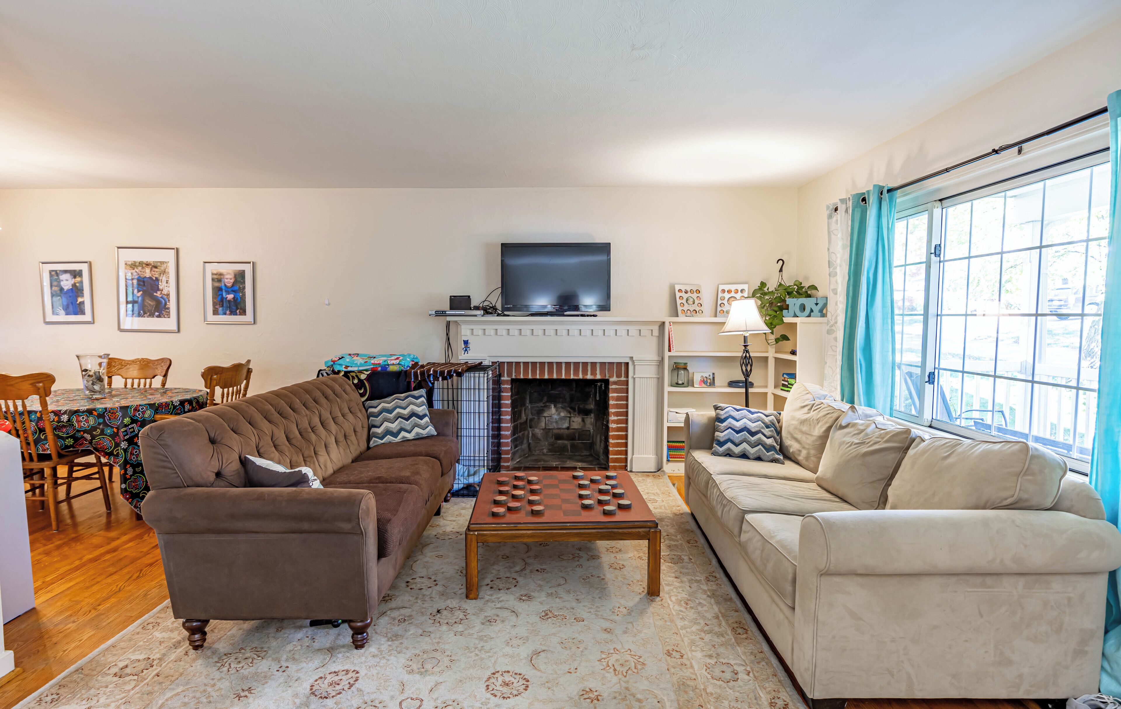 A living room with a fireplace, a television, and a chessboard.