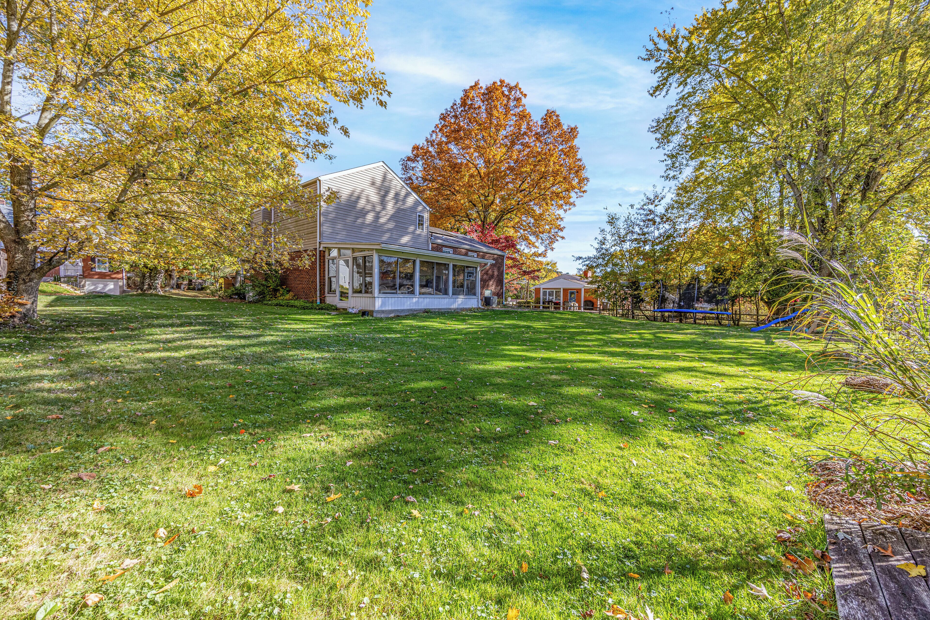 A residential house with a covered porch, a well-maintained lawn, and autumn foliage.
