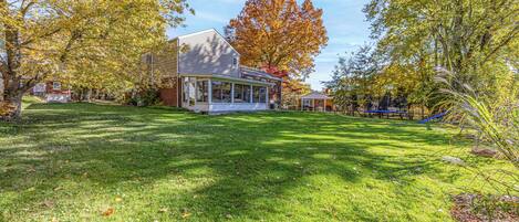 A residential house with a covered porch, a well-maintained lawn, and autumn foliage.