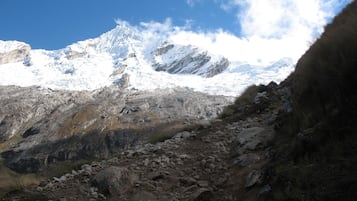 A rugged mountain landscape with rocky terrain and snow-capped peaks under a clear sky.