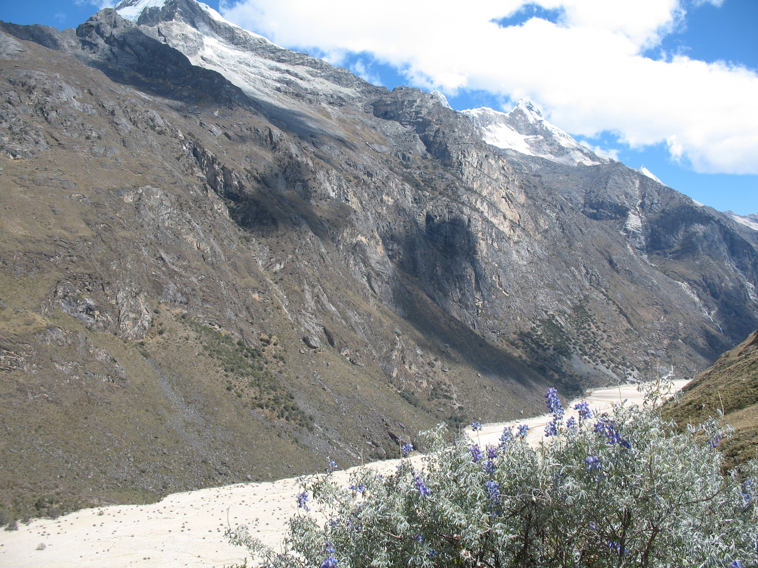 A mountainous landscape with a valley and a snow-capped peak.