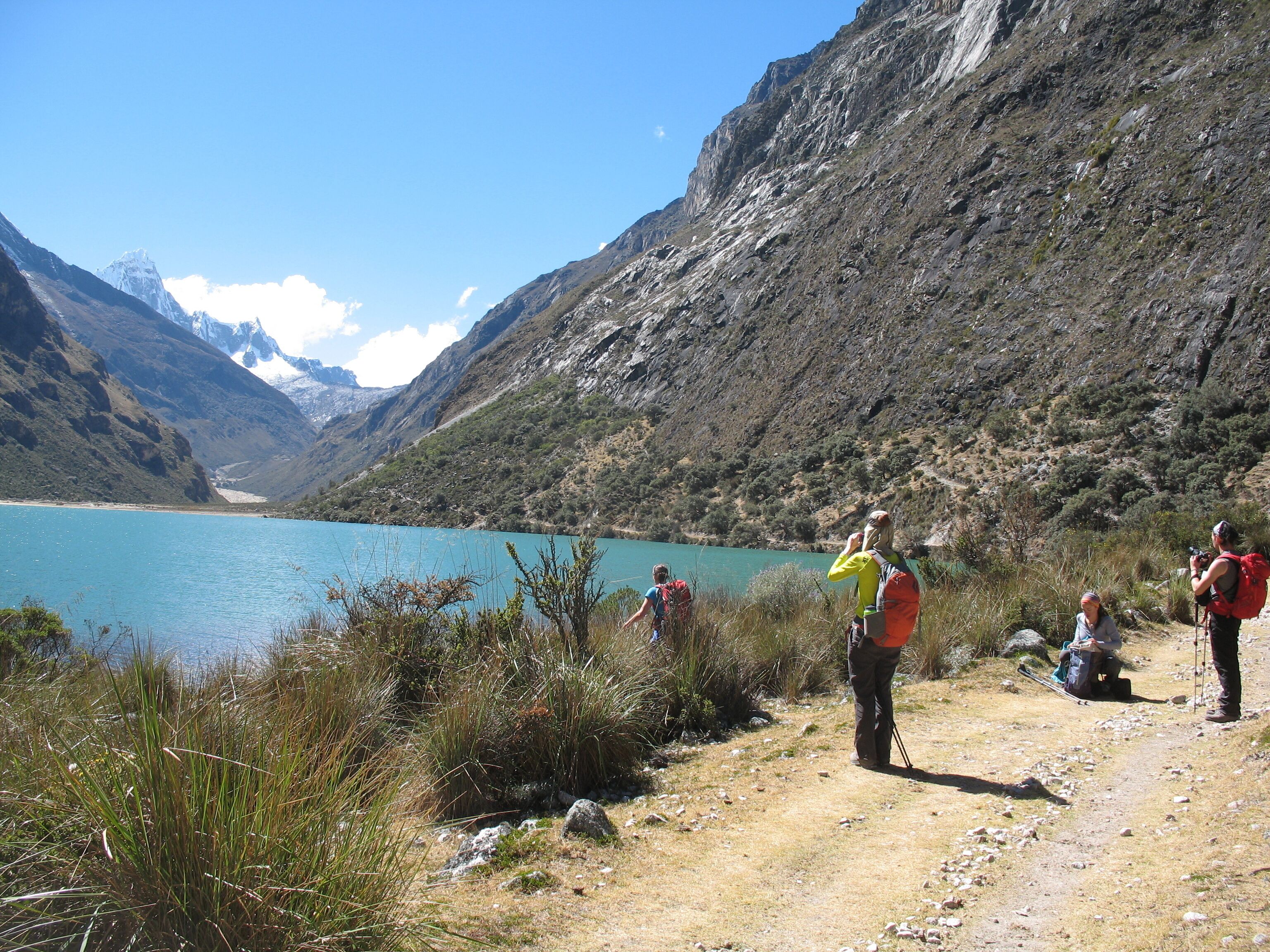 A mountainous landscape with a clear lake, rocky terrain, and hikers.