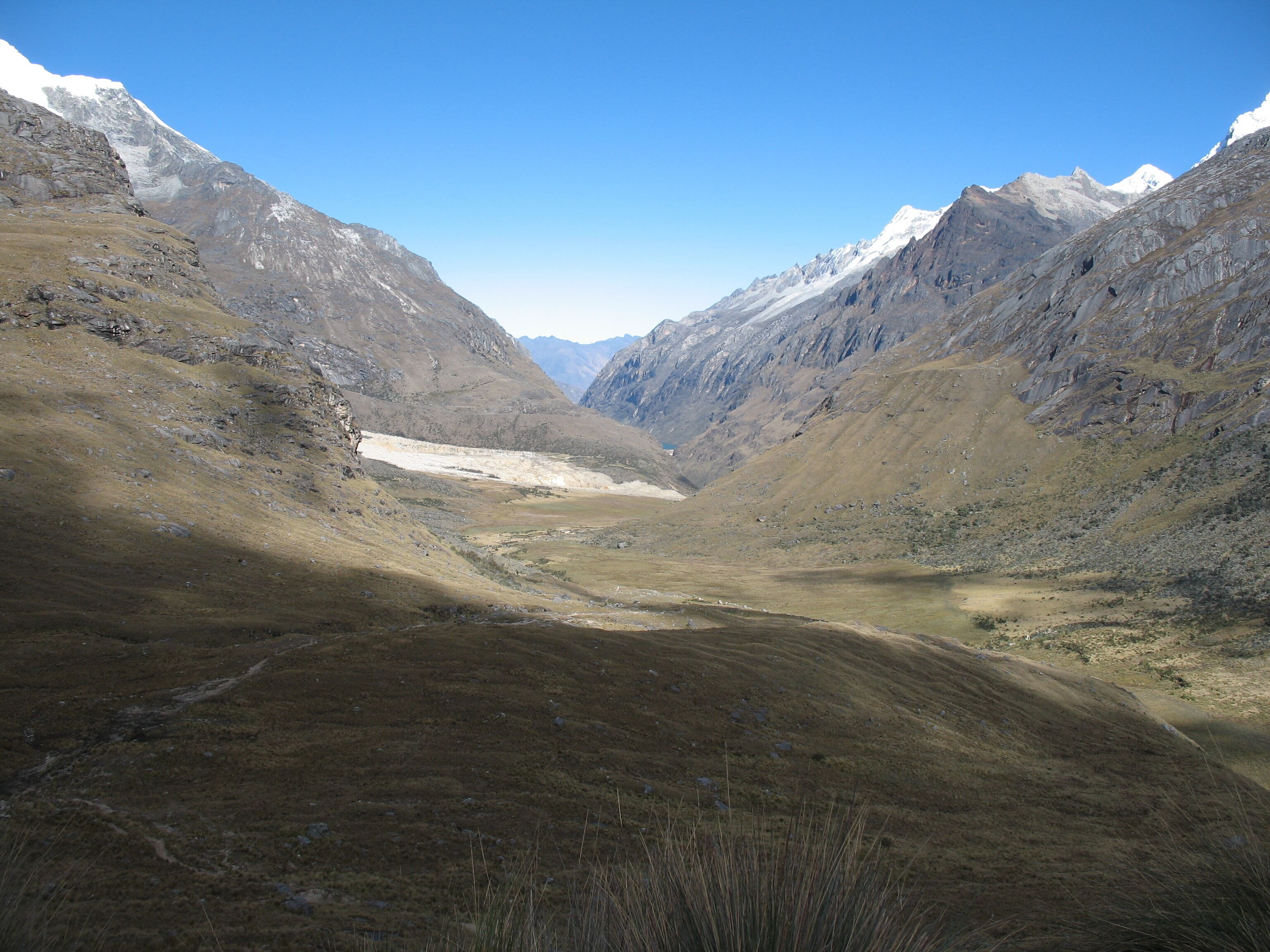 A mountainous landscape with a valley and snow-capped peaks.