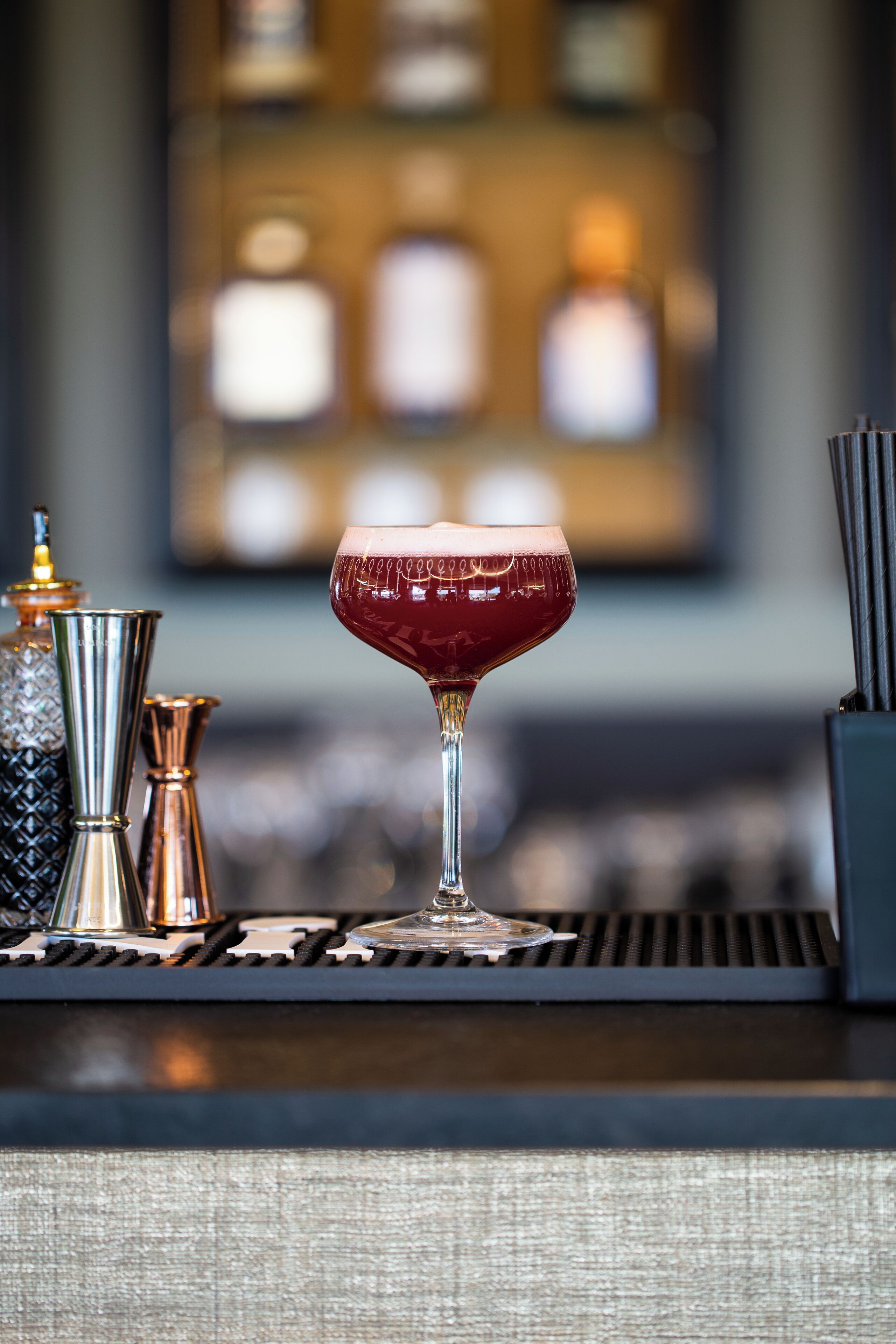 Een barsetting met een glas rode drank, een metalen kan en een zout- en peperstel.