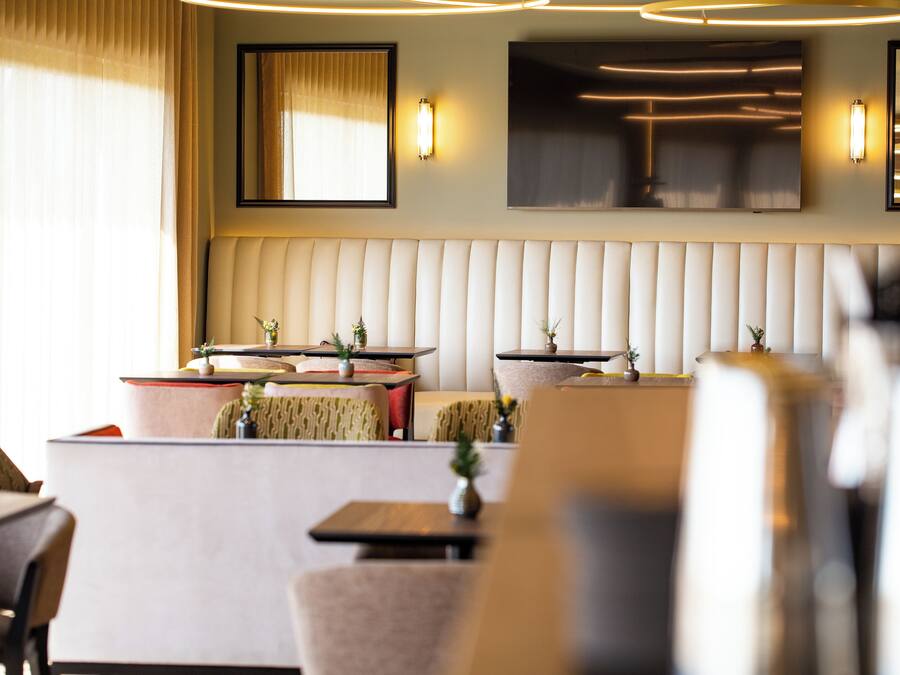 Un hall d’hôtel moderne, doté d’un espace salon, de tables et de plantes décoratives.