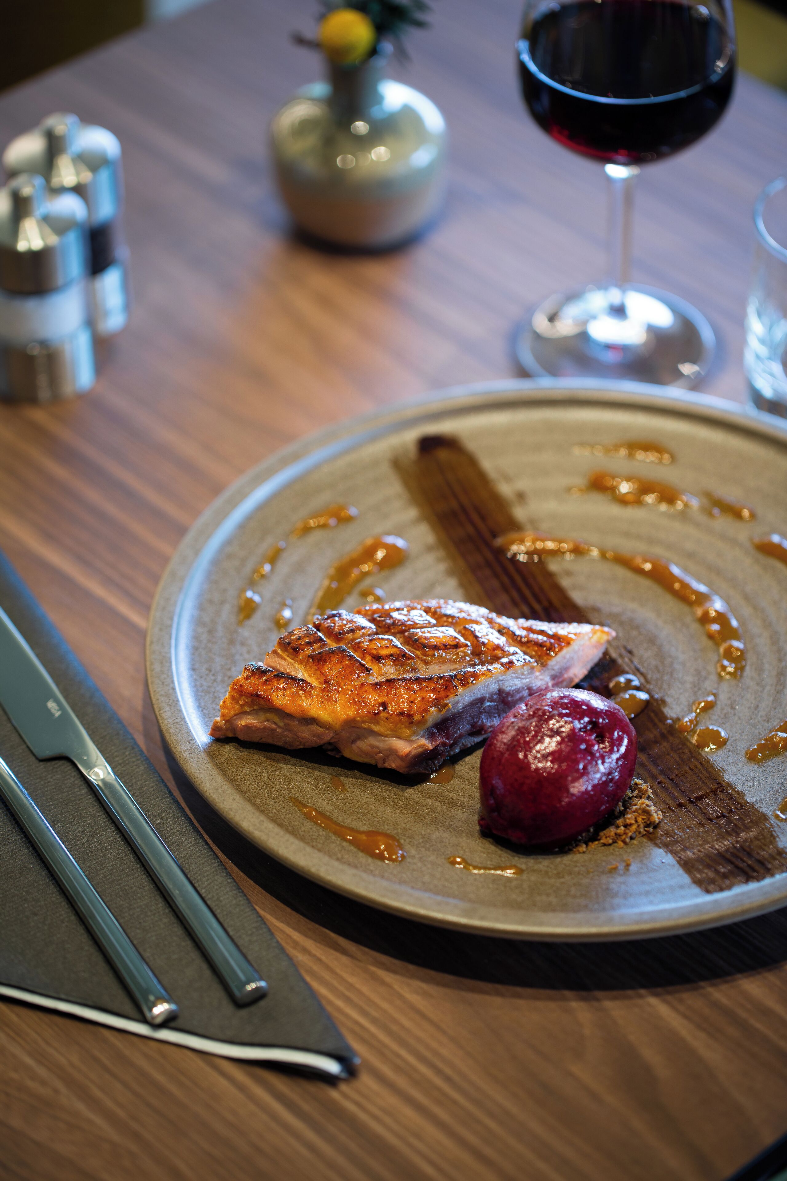 Un plato con salmón a la parrilla, una rebanada de pan y una fruta roja sobre un plato de cerámica.