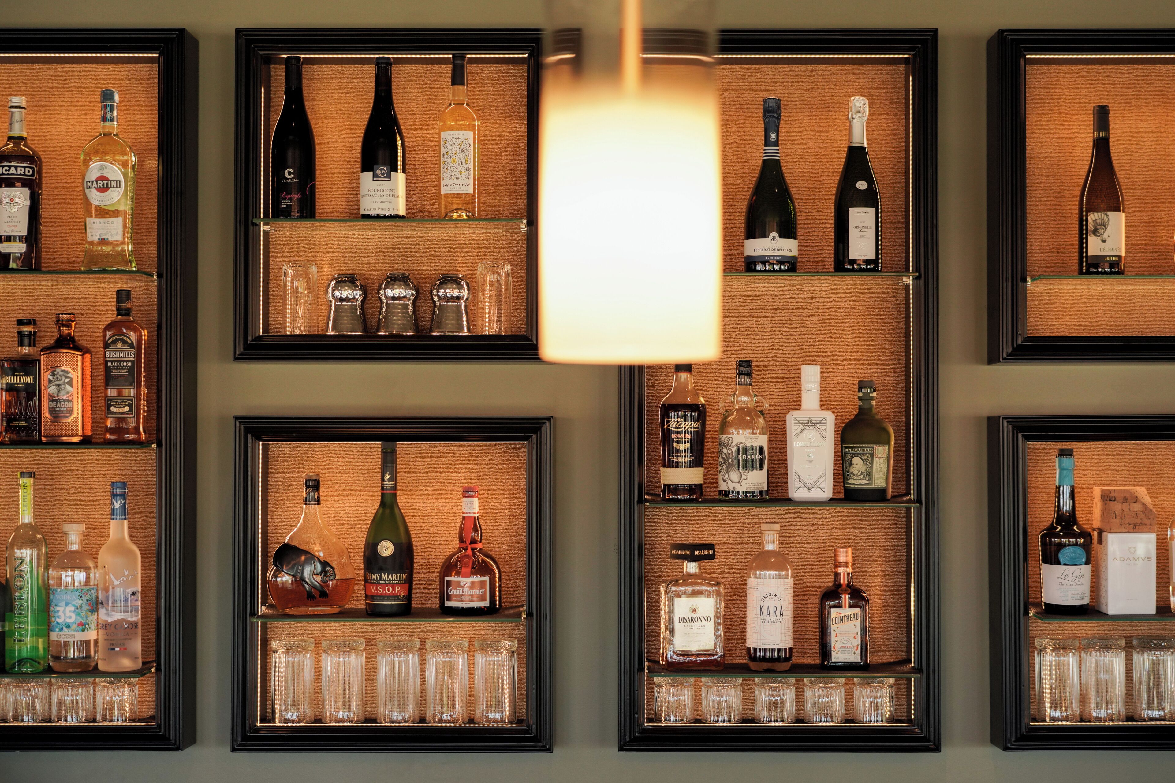 A wall of framed liquor displays with various bottles and glasses.