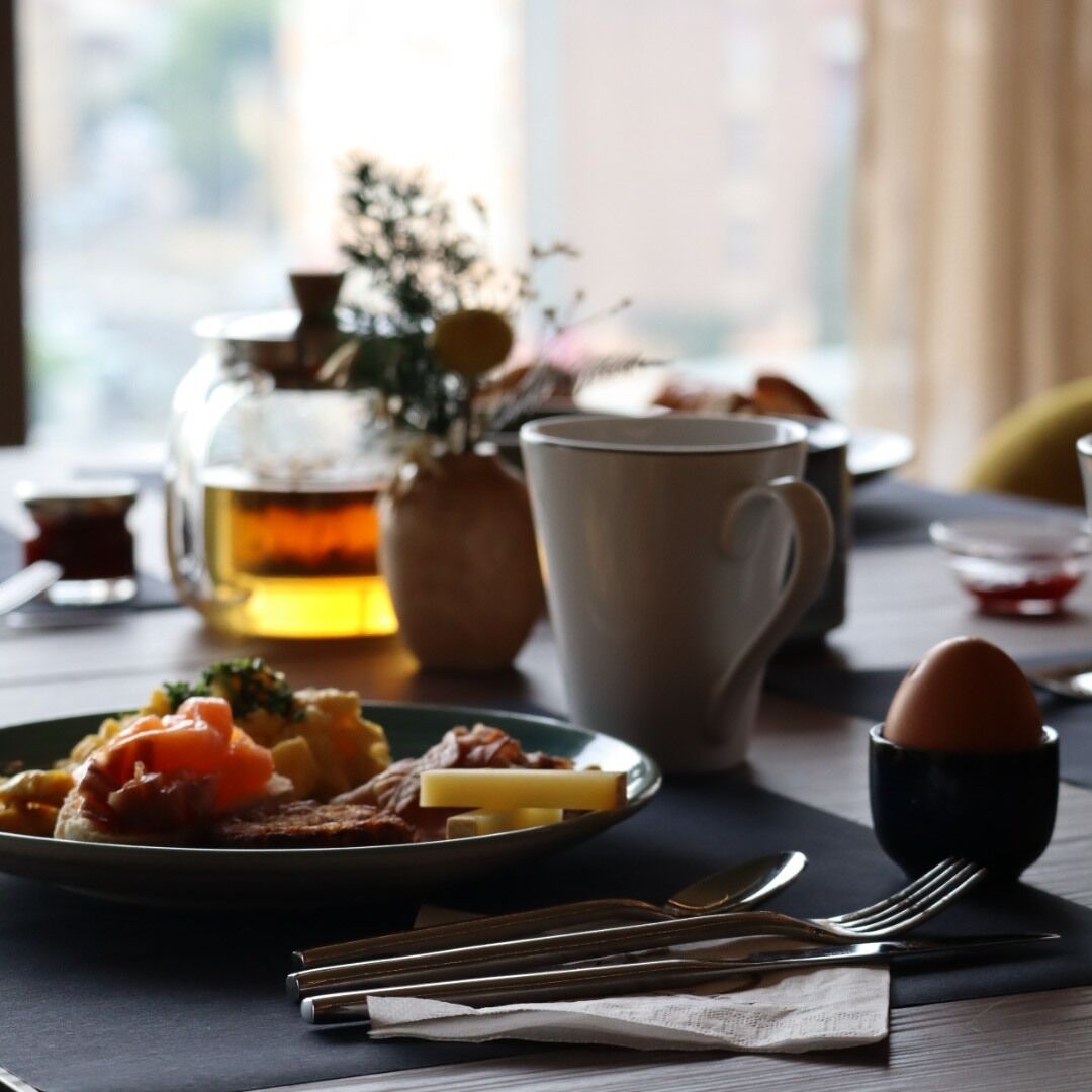Un desayuno con un plato de comida, una taza, una tetera y una taza de té.