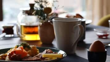 Un desayuno con un plato de comida, una taza, una tetera y una taza de té.