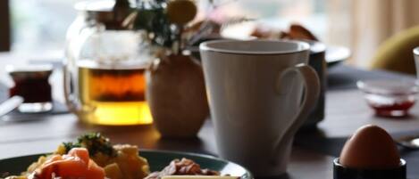 Un desayuno con un plato de comida, una taza, una tetera y una taza de té.