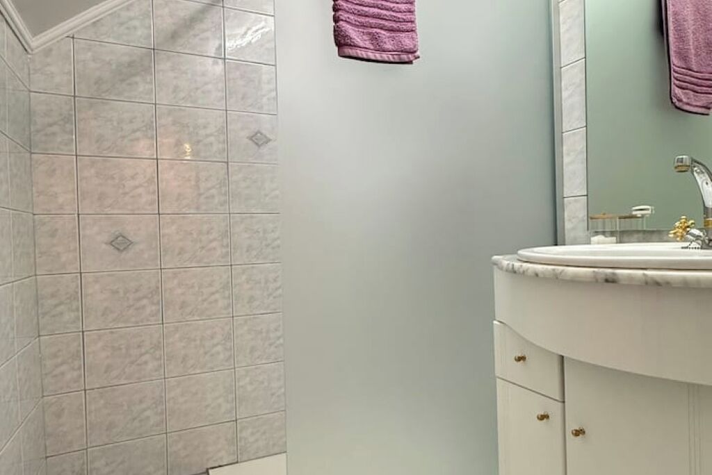 Une salle de bain avec un meuble-lavabo blanc, un miroir et un lavabo.
