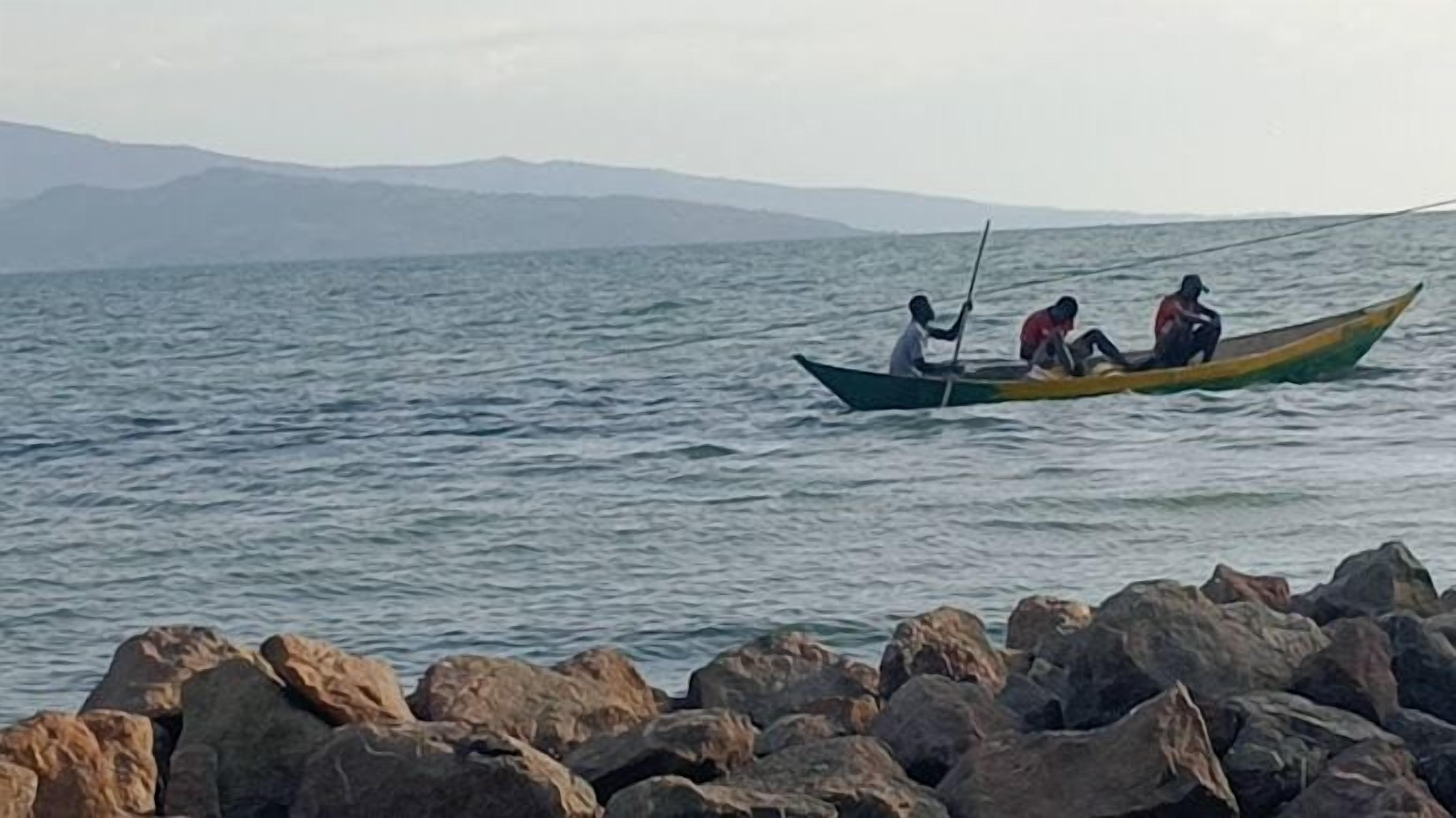 Una costa rocosa con un bote llevando a tres personas.