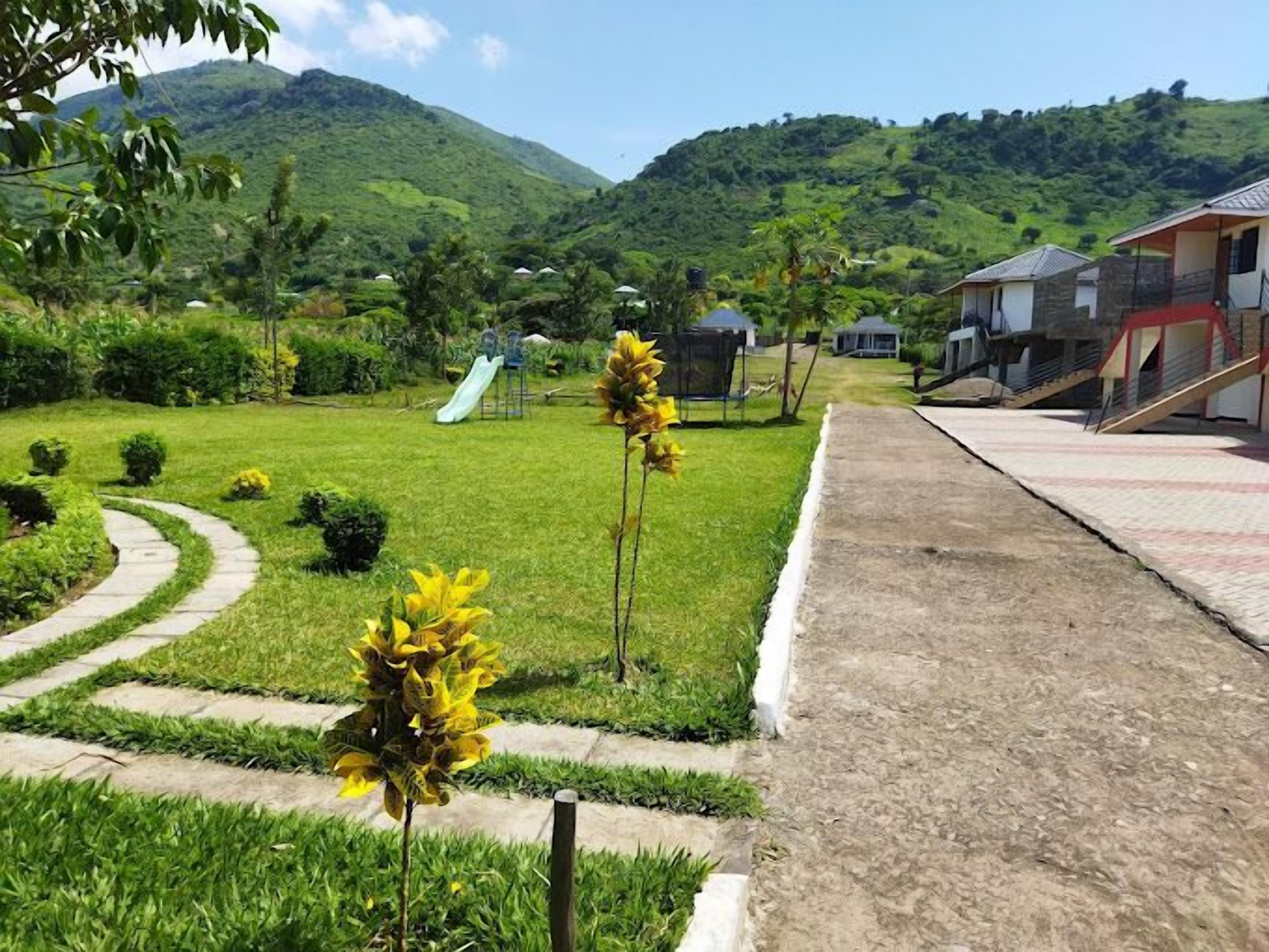 A residential area with a playground, a pathway, and houses with a view of green hills.