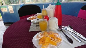 Un tavolo imbandito con frutta, bevande, salse e posate.