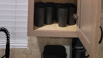 A wooden cabinet with shelves holding black bowls and cups.