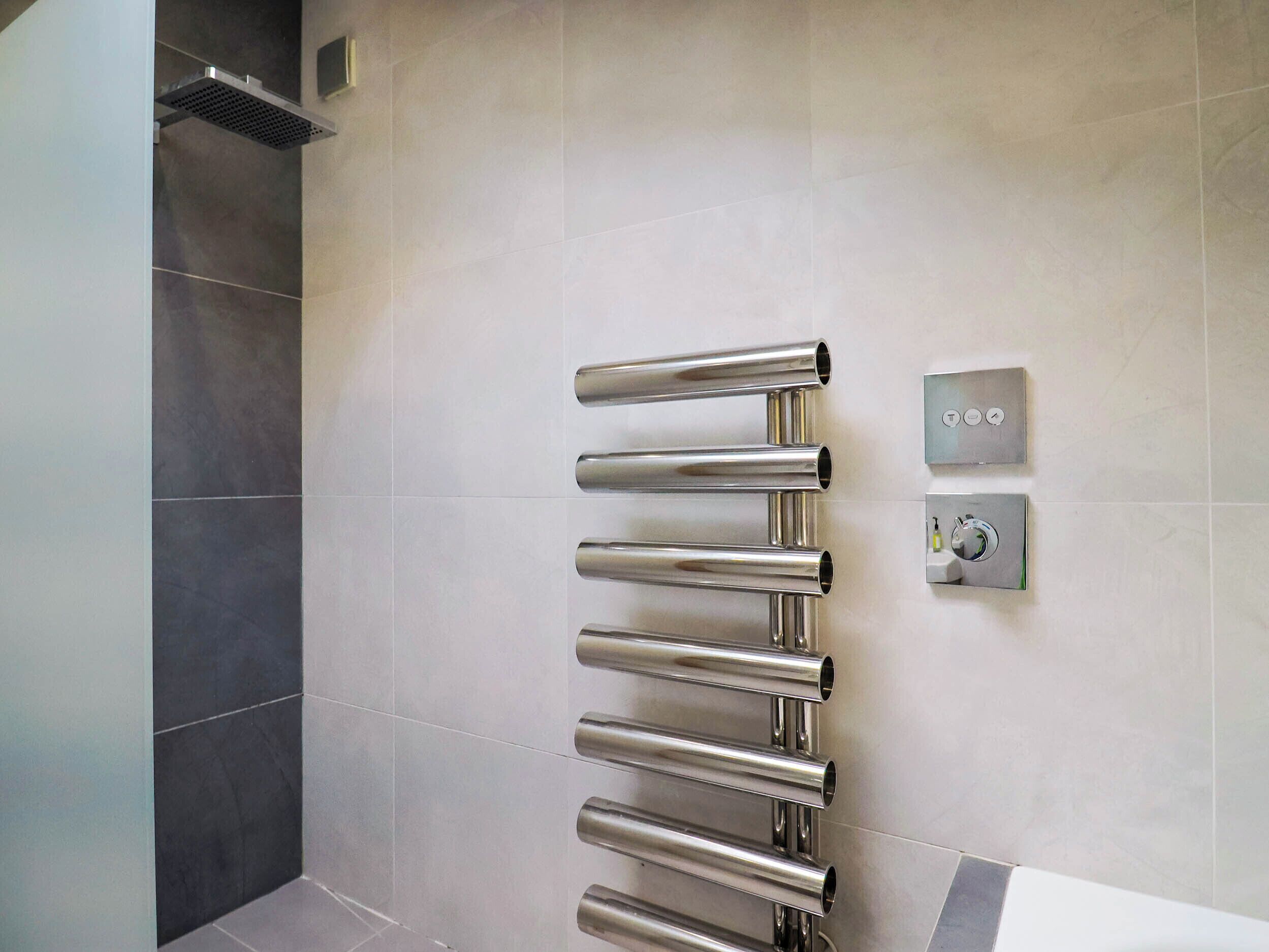 A bathroom with a wall-mounted towel rack and a control panel.