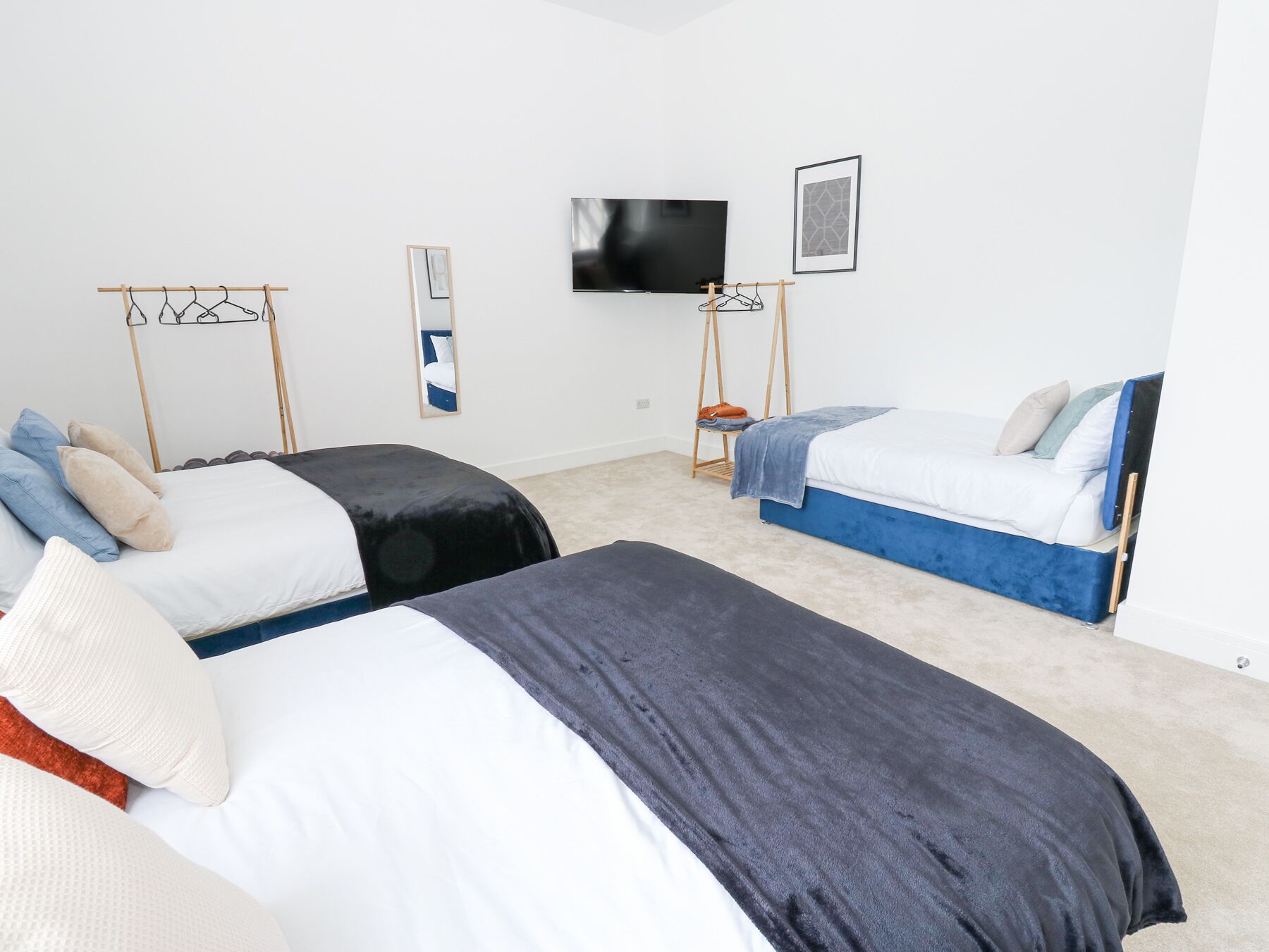 Ein Hotelzimmer mit zwei Betten, einem Fernseher, einem Spiegel und einem gerahmten Bild an der Wand.