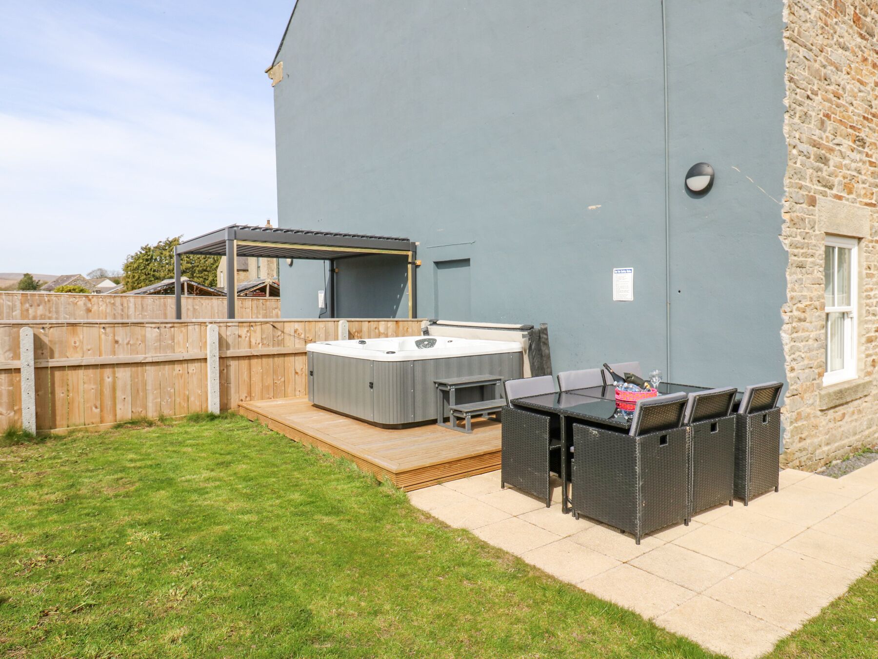 Un patio con jacuzzi, mobiliario exterior y una pérgola.