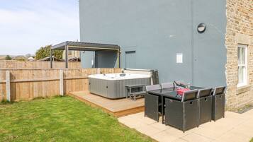 Un patio con jacuzzi, mobiliario exterior y una pérgola.