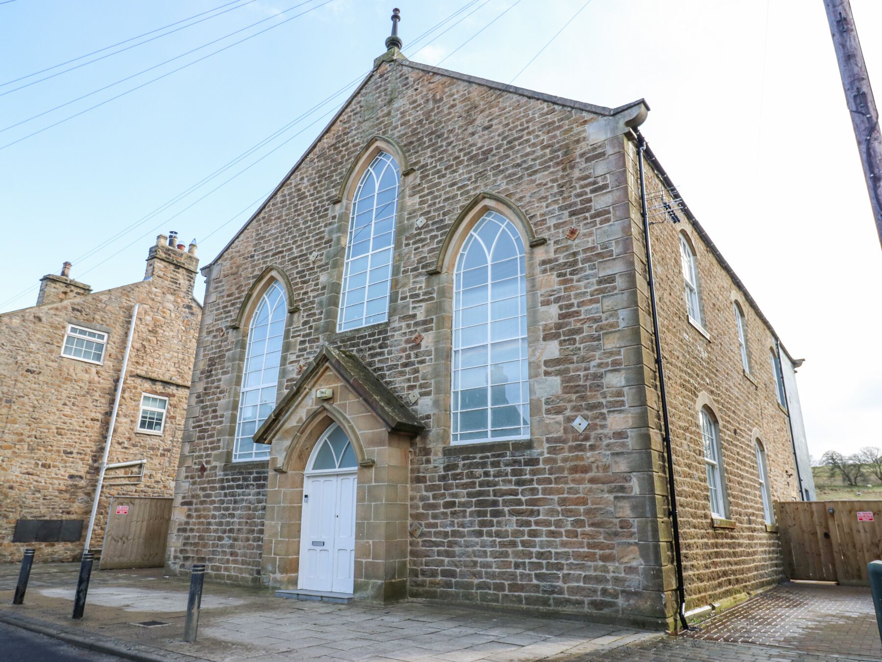 A stone church with a white door and two large arched windows.