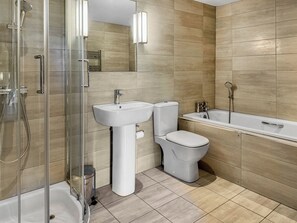 A modern bathroom with a glass-enclosed shower, a white pedestal sink, a toilet, and a bathtub.