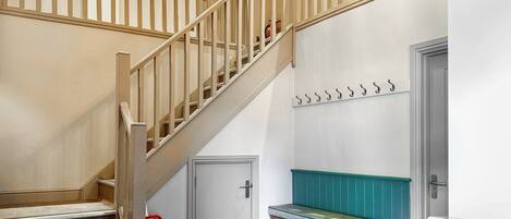 Una escalera con barandillas de madera, un extintor, un banco y un perchero de pared.