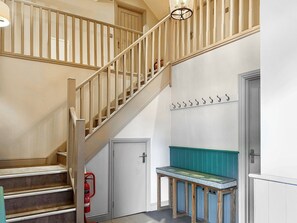 A staircase with wooden railings, a fire extinguisher, a bench, and a wall-mounted coat rack. - Barn Owl Cottage - UK48510 (Kirk Hammerton, near York)