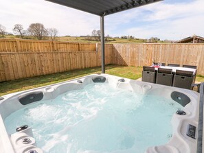 Ein Whirlpool mit Holzzaun und Gartenmöbeln im Hintergrund.
