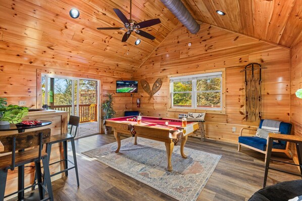 A cozy cabin with a pool table, a television, and a ceiling fan. - Moonlight Haven by Ghosal Luxury Lodging (Pigeon Forge)