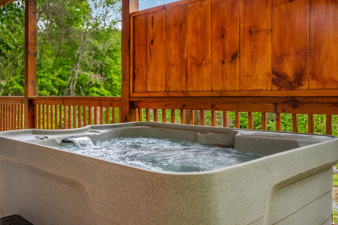 A hot tub under a wooden deck with a natural backdrop.
