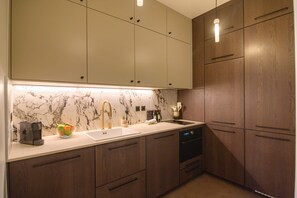 A modern kitchen with marble backsplash, wooden cabinets, and a built-in dishwasher. - Balcon Champs Elysees (Paris)