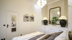 A bedroom with a bed, bedside tables, a dresser, a mirror, and wall-mounted lights. - Balcon Champs Elysees (Paris)