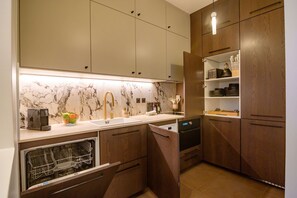 A modern kitchen with wooden cabinets, a marble backsplash, and a built-in dishwasher.