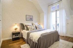 A bedroom with a bed, nightstand, and a view of the outdoors. - Balcon Champs Elysees (Paris)